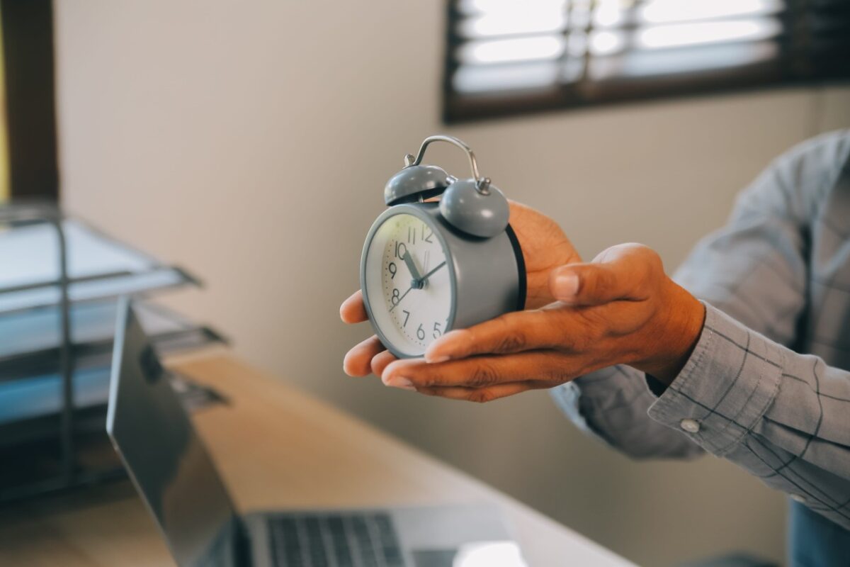 A person holds a silver twin-bell alarm clock