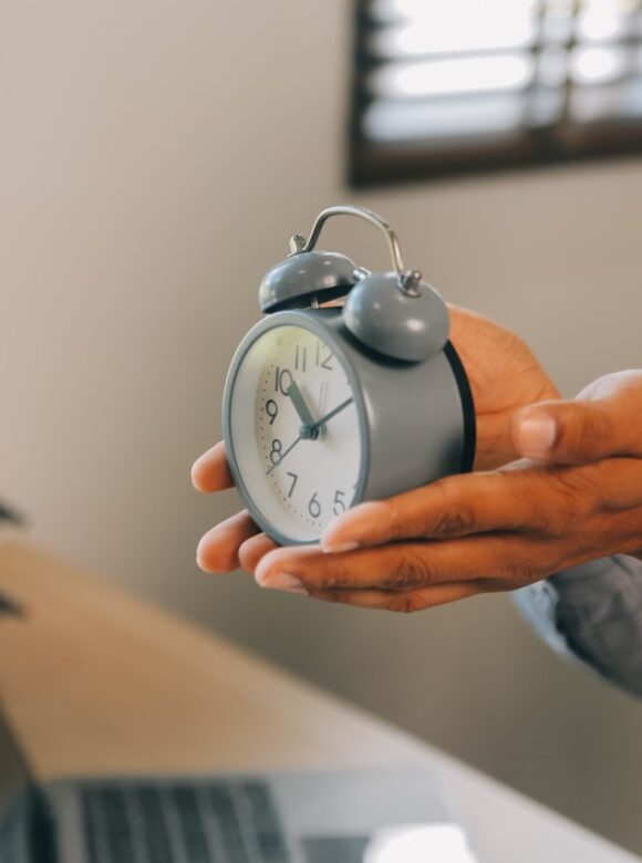 A person holds a silver twin-bell alarm clock