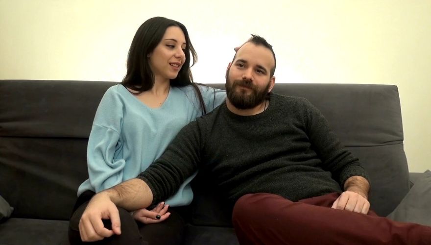 Couple sitting closely together on a couch while talking about their relationship.