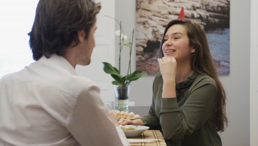 Couple sitting across from each other and talking over a meal at home