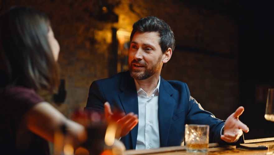 Couple having a deep conversation over drinks in a warmly lit restaurant.